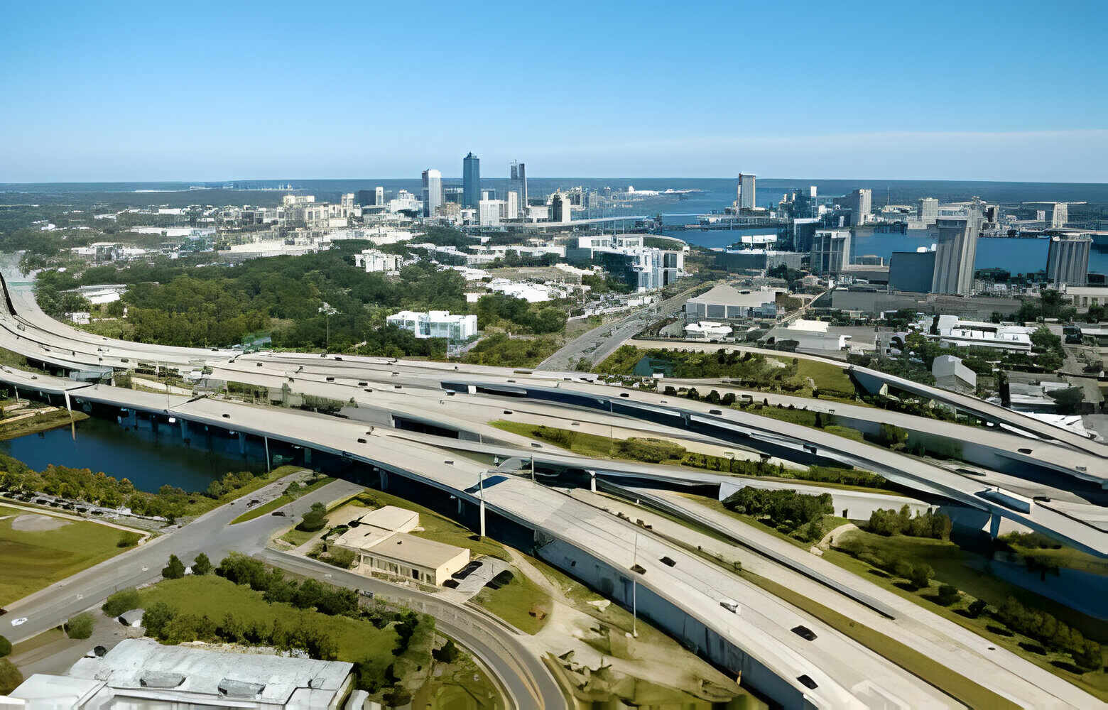 Aerial view of Jacksonville city with high office buildings and american freeway intersection with fast driving cars and trucks.