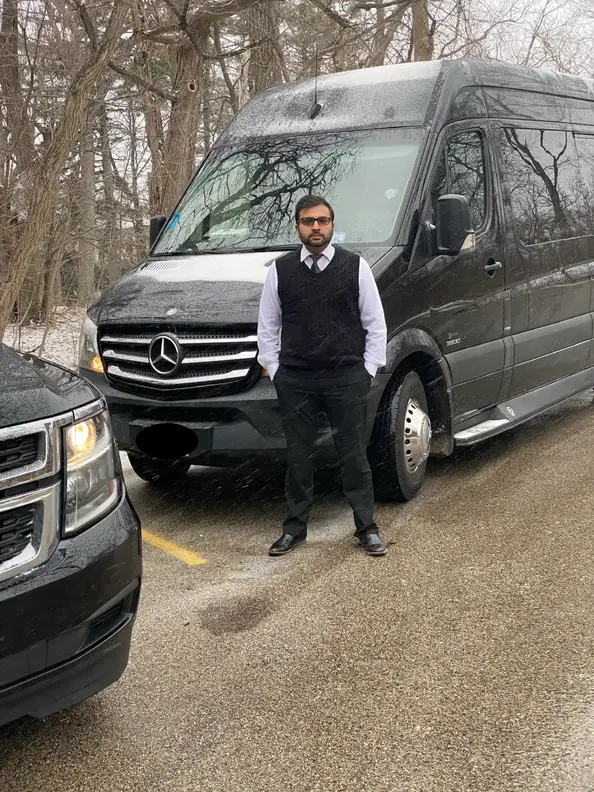 Chauffeur Stands in front of Sprinter Van